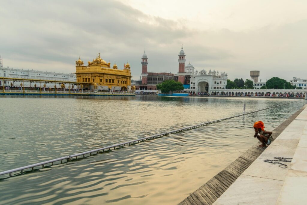Serene view of the Golden Temple in Amritsar, India, with a child near the reflective waters.